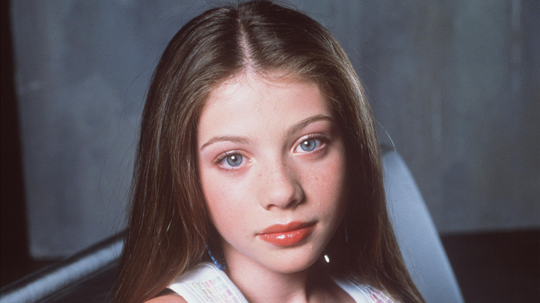 A young Michelle Trachtenberg softly smiles