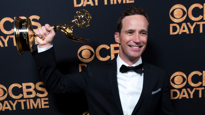 Mike Richards holding an Emmy Award