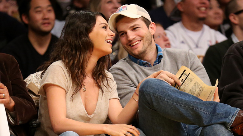 Mila Kunis and Ashton Kutcher smiling in a crowd