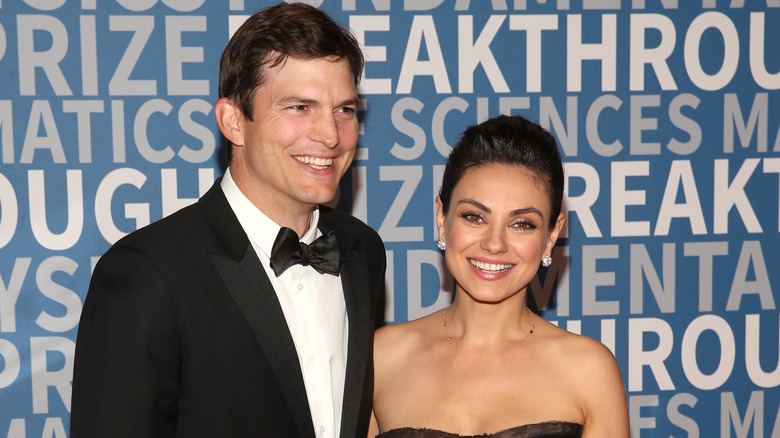 Ashton Kutcher and Mila Kunis smiling on the red carpet