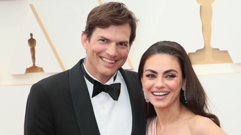 Ashton Kutcher and Mila Kunis laugh while posing at event