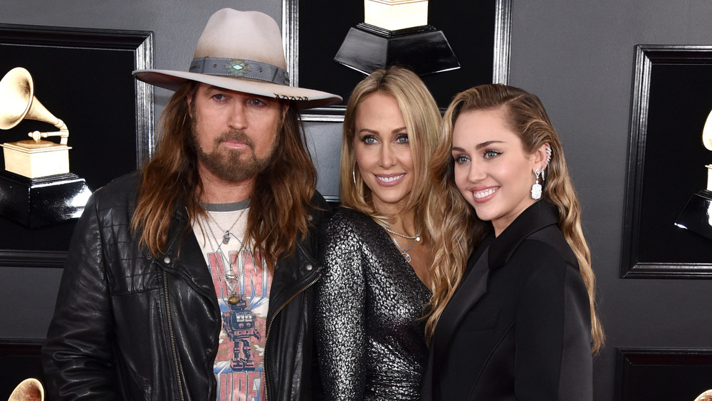 Miley Cyrus smiling with Billy Ray Cyrus and Tish Cyrus