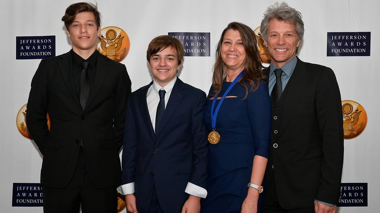 Jake and Romeo Bongiovi, Dorothea Hurley, and Jon Bon Jovi smiling