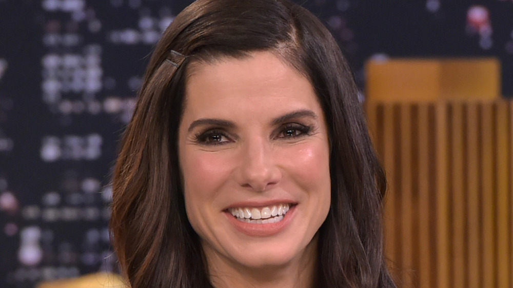 Sandra Bullock sitting on a couch smiling