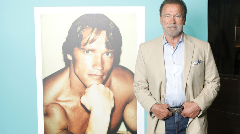 Arnold Schwarzenegger posing beside a photo