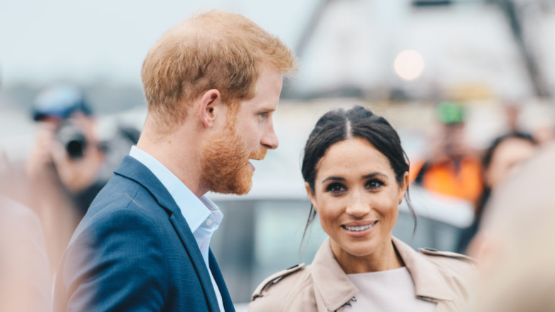 Prince Harry and Meghan Markle smiling in a crowd