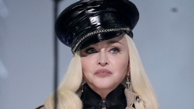 Madonna in black hat, smirking