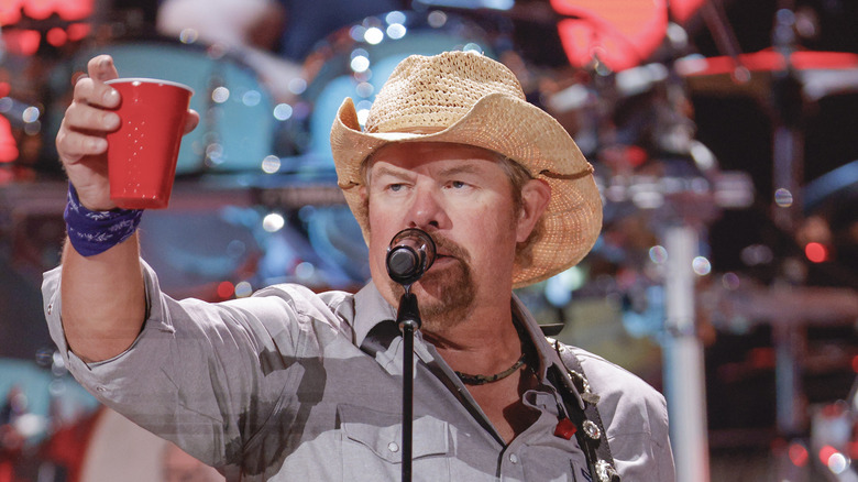 Toby Keith raising a red cup during concert 