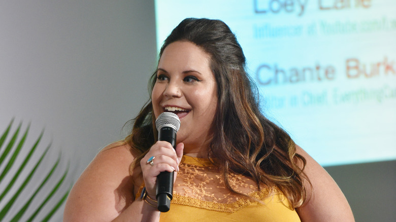 Whitney Way Thore, speaking into a microphone at an event