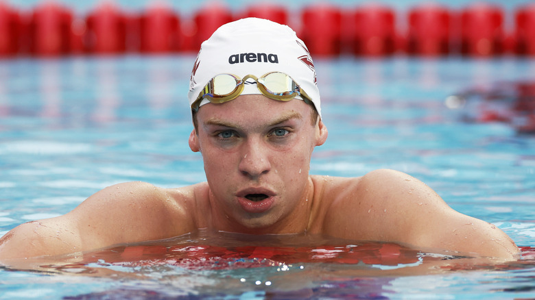 Leon Marchand holding onto pool lane line