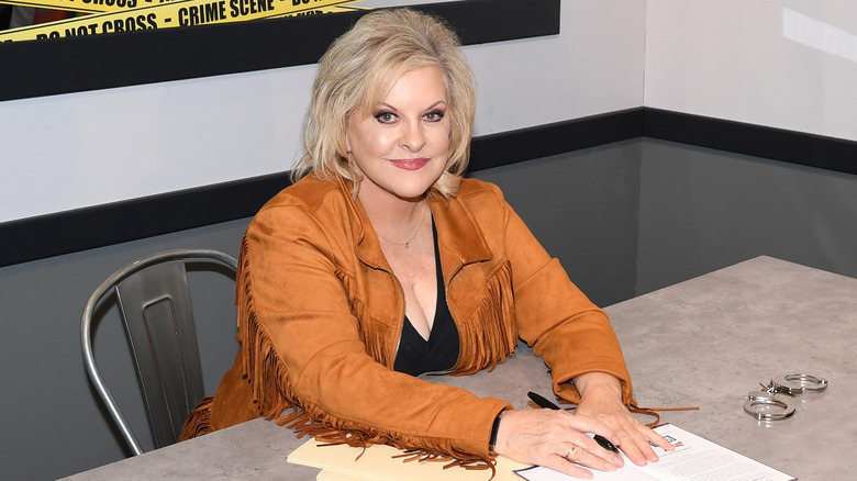 Nancy Grace smiling and sitting at a table