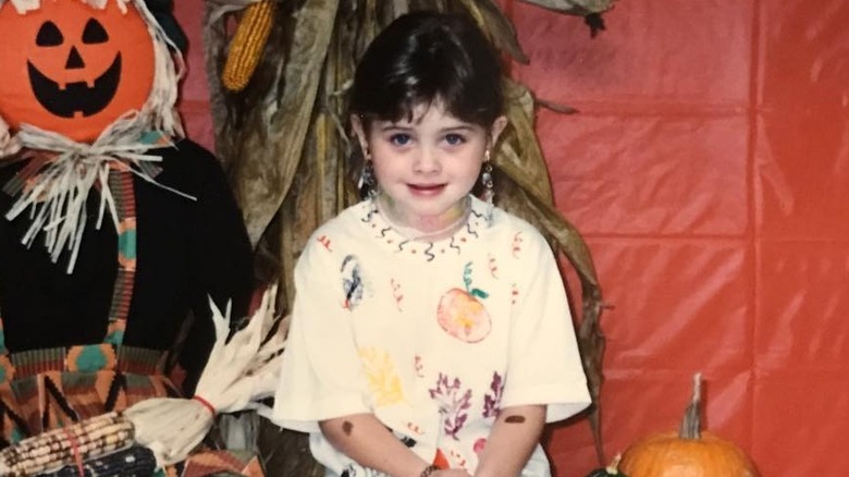 Young Natalia Dyer with jack-o'-lantern scarecrow