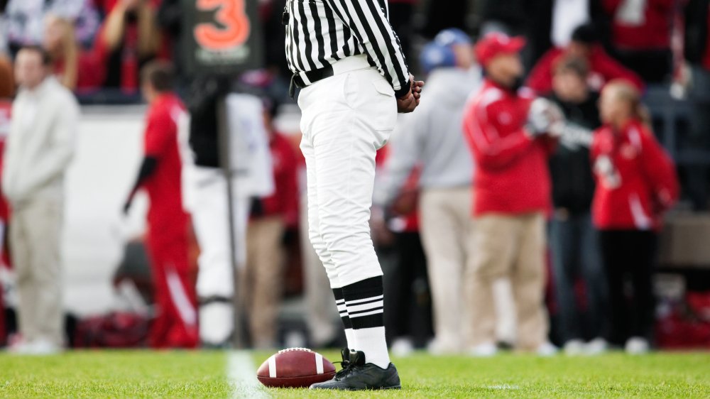 NFL referee with ball on sideline 