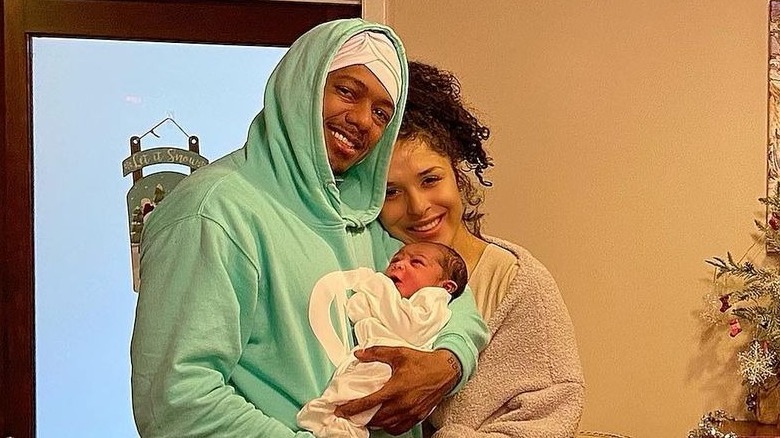 Nick Cannon and Brittany Bell posing with child