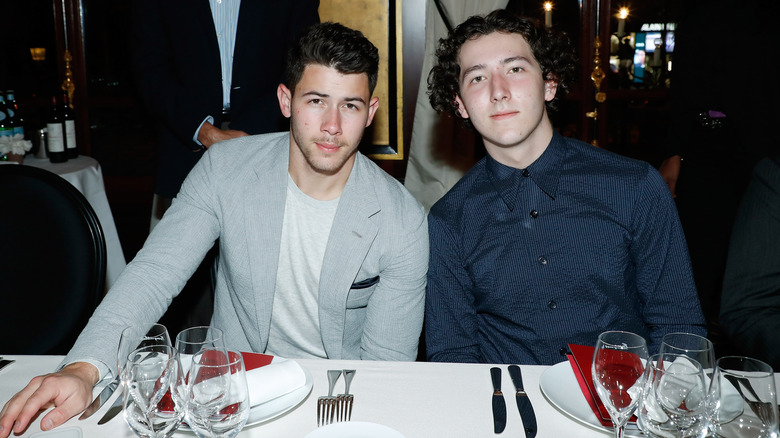 Nick Jonas and Frankie Jonas sit together at an event