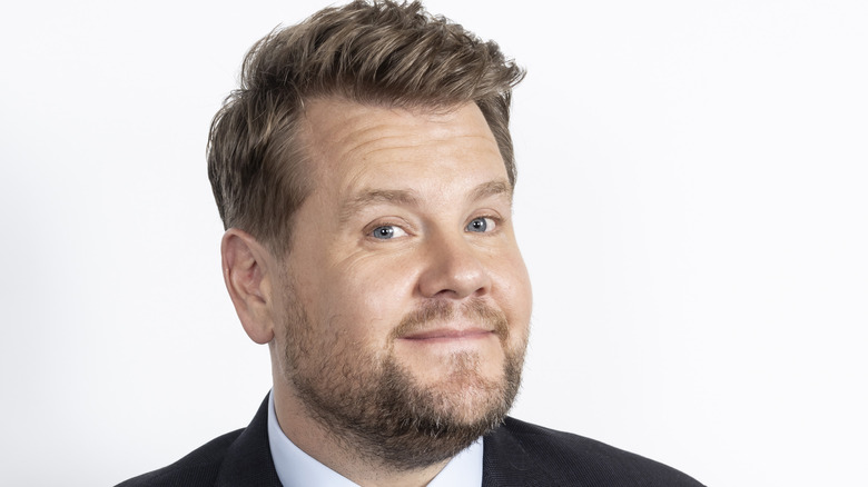 James Corden smiles in front of a white background