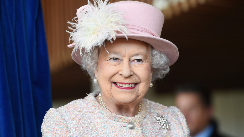 Queen Elizabeth II smiling in light pink