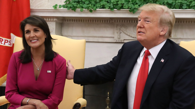 Nikki Haley smiling while Donald Trump touches her arm
