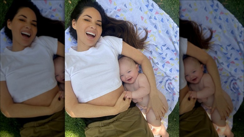 Olivia Munn lying on the grass with her son