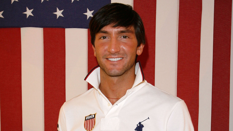 Evan Lysacek smiling in front of American flag