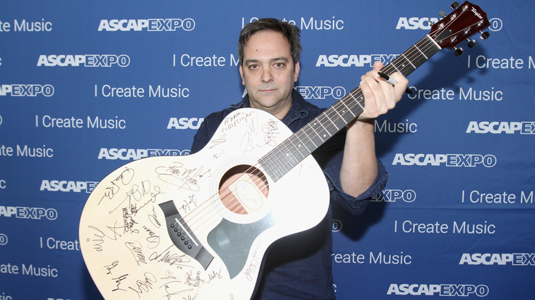 Adam Schlesinger holding a giant guitar.