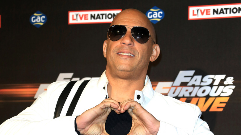 Vin Diesel wearing sunglasses and making a heart with his hands