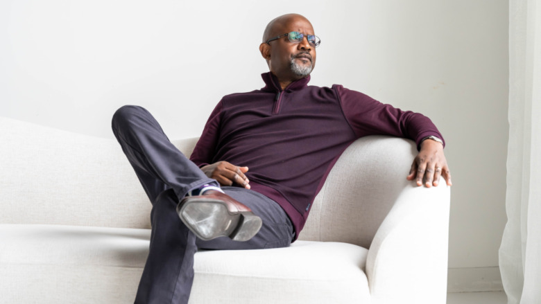 Pastor Calvin Roberson posing on a couch for a portrait 