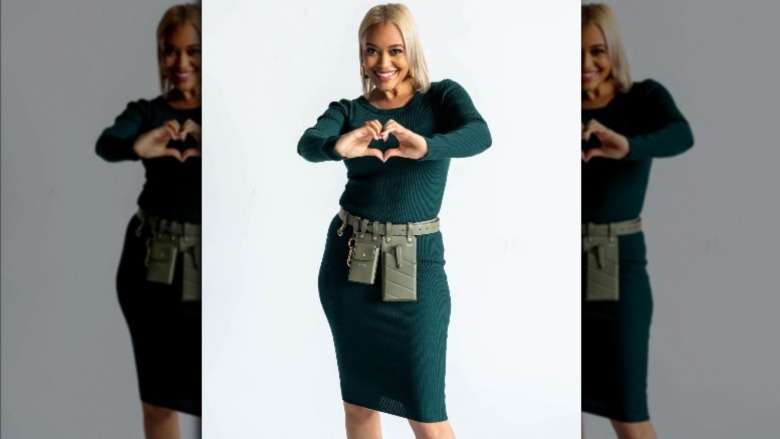 Unmatchables star Stephanie wearing utility belt and making heart hands 