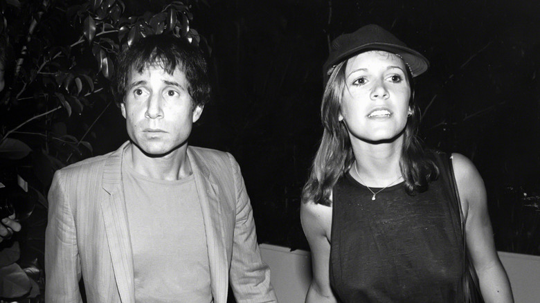 Paul Simon holding hands with Carrie Fisher