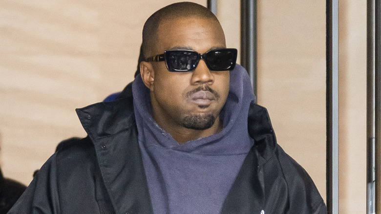 Kanye West wearing a gray hoodie and dark glasses