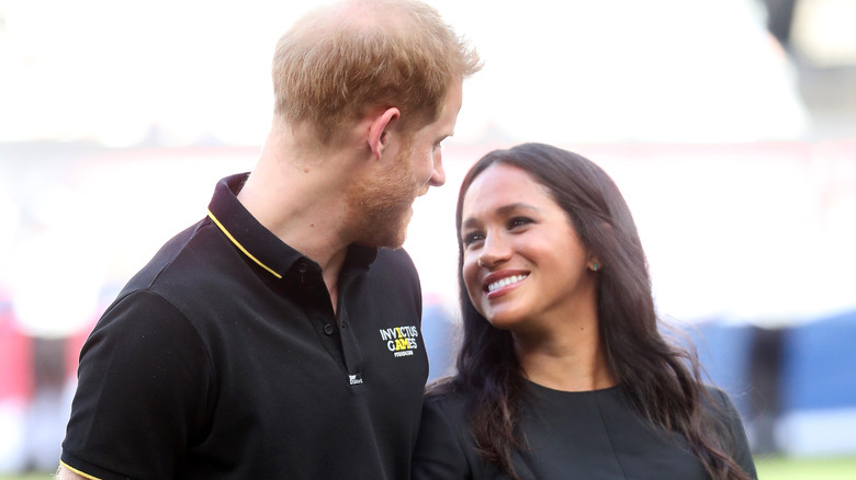 Prince Harry and Meghan Markle smiling at each other