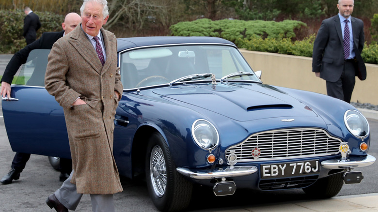 Prince Charles walking next to his Aston Martin