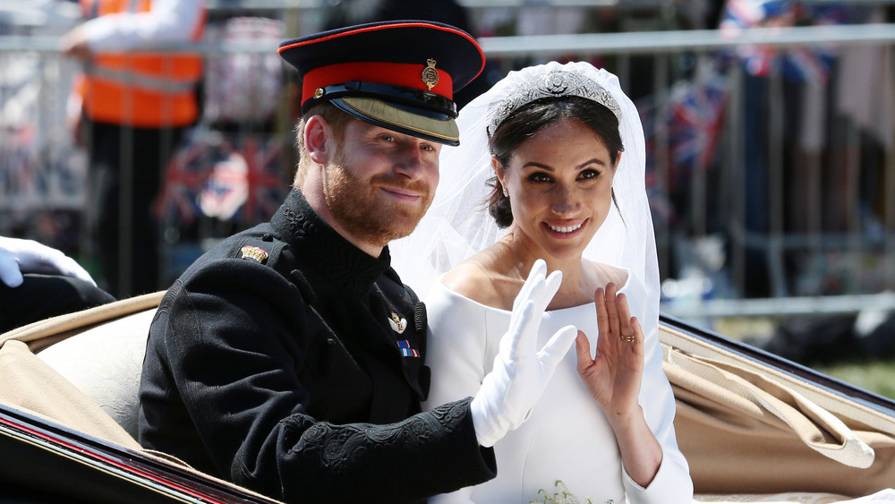 Prince Harry and Meghan Markle smiling and waving to fans on their wedding day 