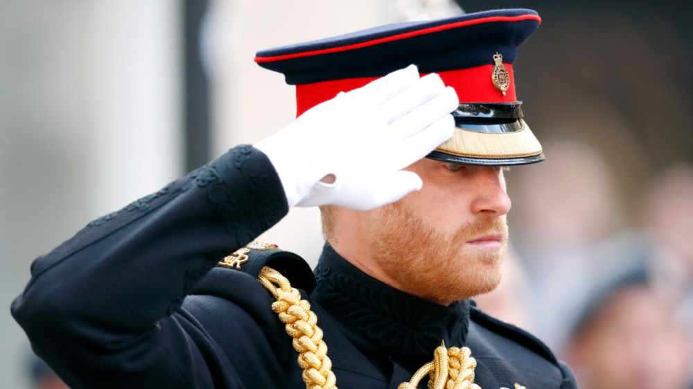 Prince Harry, in full military uniform, saluting, looking serious