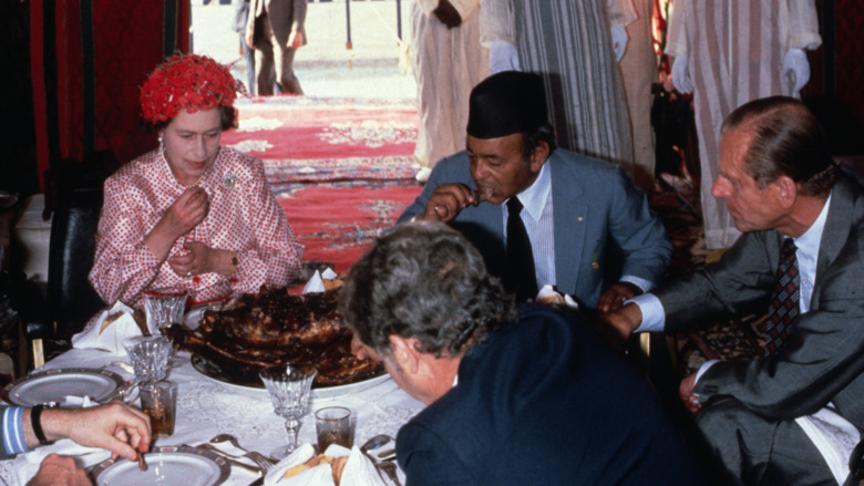 Queen Elizabeth eating with her hands looking unhappy