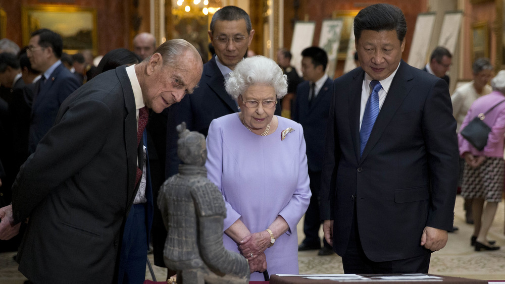 Prince Philip, Queen Elizabeth, and Xi Jinping looking at artefacts