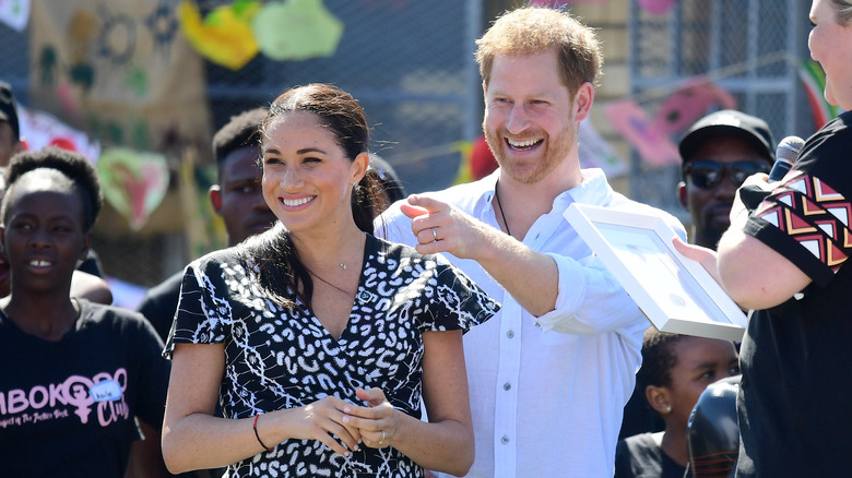 Meghan Markle and Prince Harry smiling and pointing