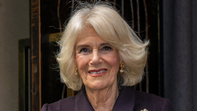 Queen Camilla wearing gold earrings and smiling