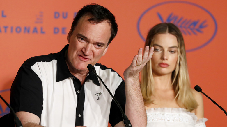 Quentin Tarantino speaking, Margot Robbie behind him