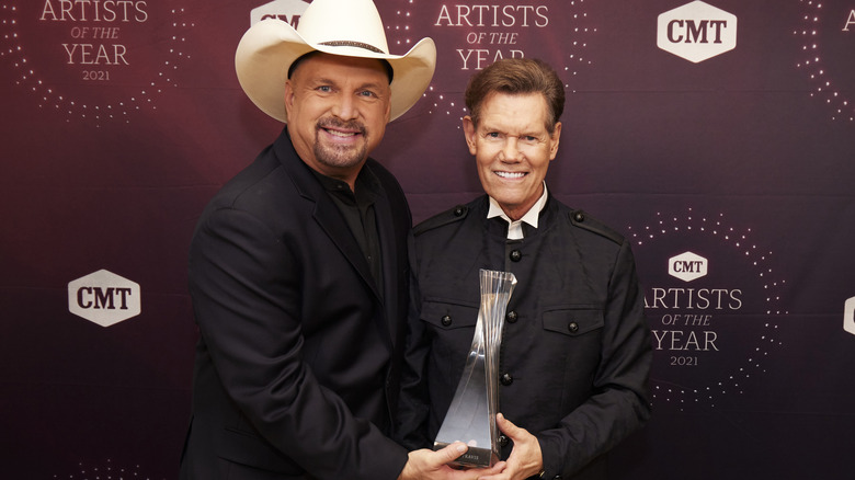 Garth Brooks and Randy Travis holding a trophy.