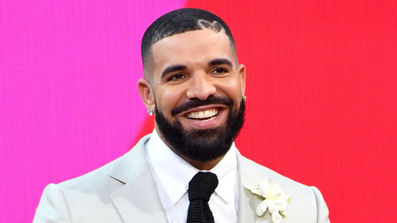 Drake grinning in a suit