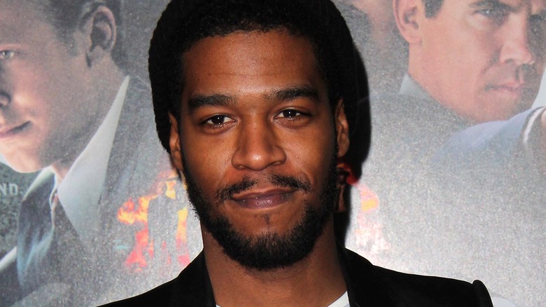 Kid Cudi standing in front of a movie poster