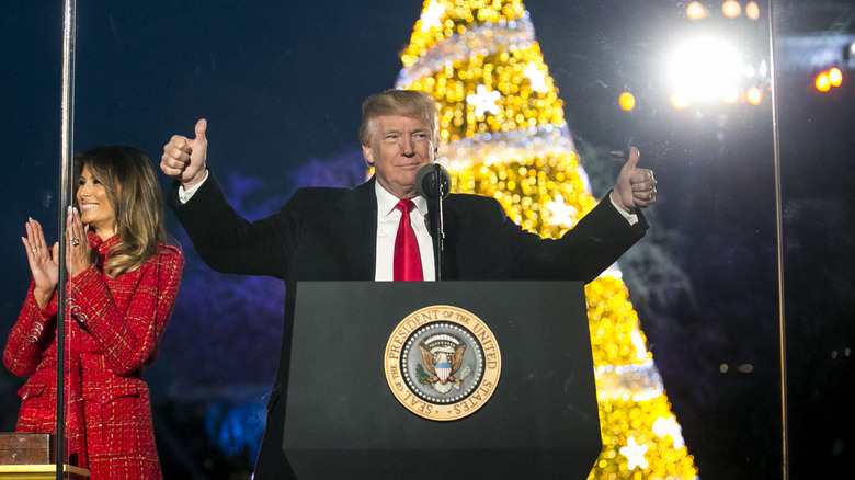 Donald Trump giving thumbs up in front of Christmas tree