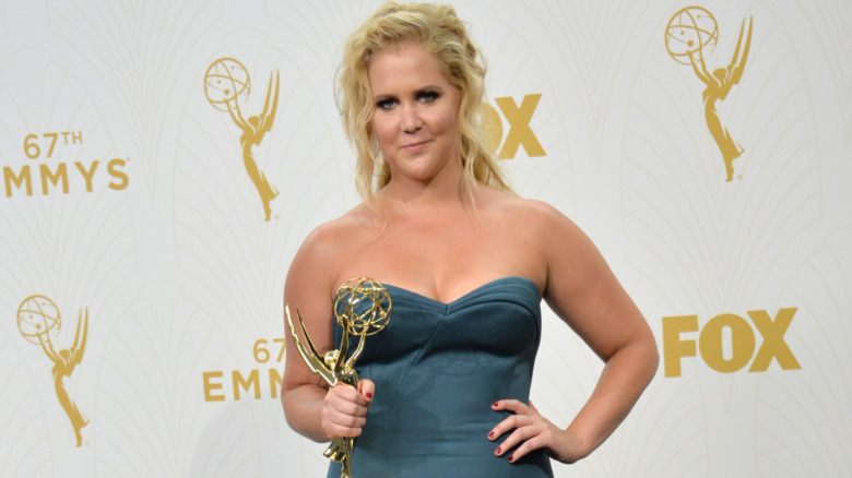 Amy Schumer smiling, holding her Emmy 