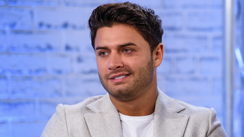  Mike Thalassitis sitting in a chair holding a microphone