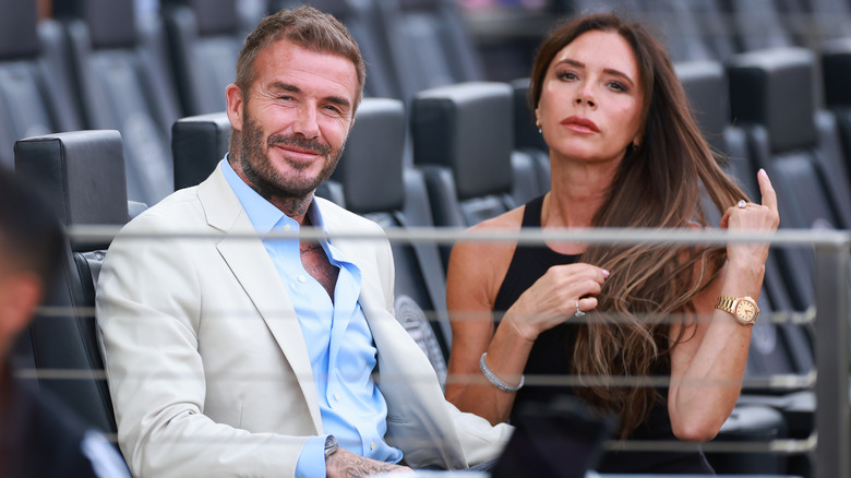 David Beckham sitting and Victora Beckham flipping her hair