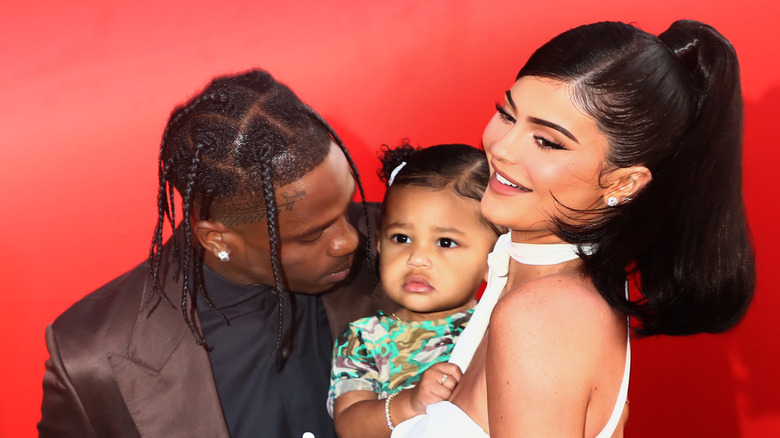 Travis Scott, Stormi, Kylie Jenner red background