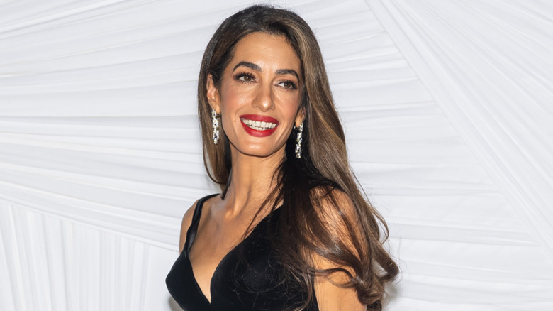 Amal Clooney smiling with red lipstick