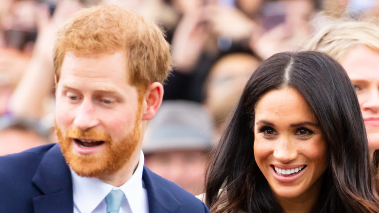 Prince Harry and Meghan Markle smiling in a crowd