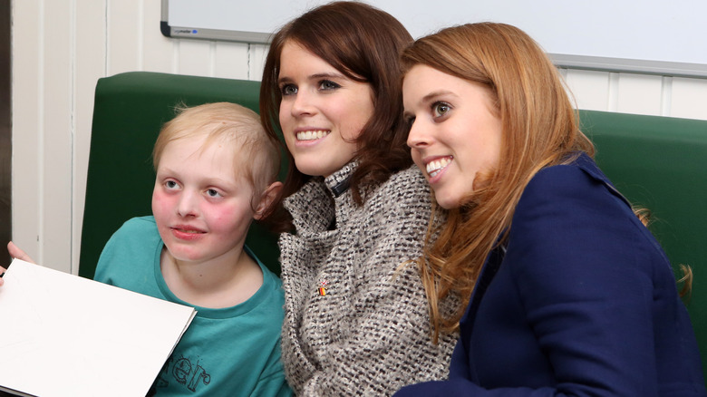 Princesses Eugenie and Beatrice posing with a cancer patient 